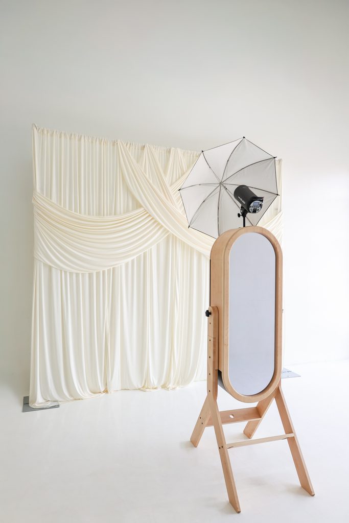 Memento mirror photo booth with studio light and ivory drape backdrop