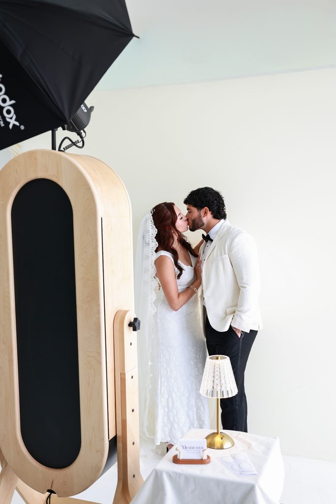 Couple sharing a kiss at the Memento mirror photo booth
